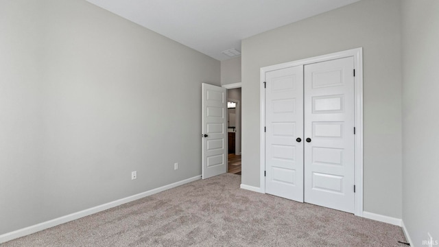 unfurnished bedroom with a closet and light colored carpet