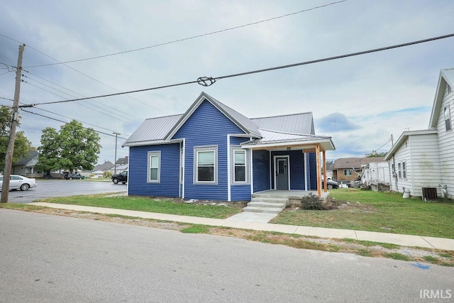 view of front of property with cooling unit, a front lawn, and covered porch