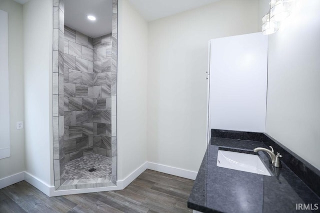 bathroom featuring tiled shower, vanity, and hardwood / wood-style floors