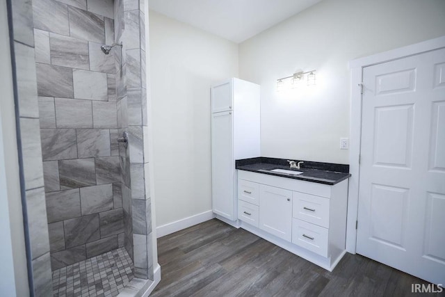 bathroom with tiled shower, vanity, and wood-type flooring