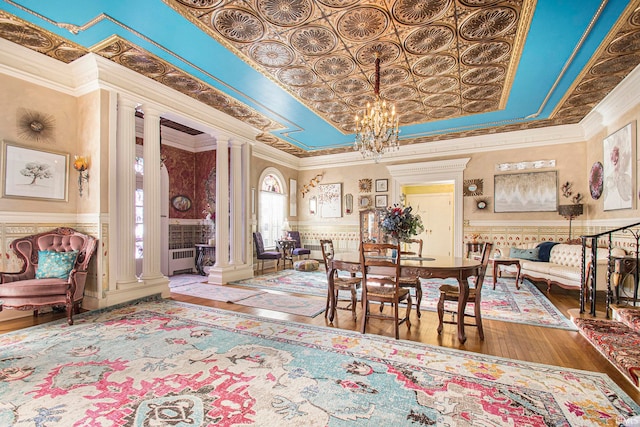 dining room with crown molding, hardwood / wood-style flooring, a chandelier, and decorative columns