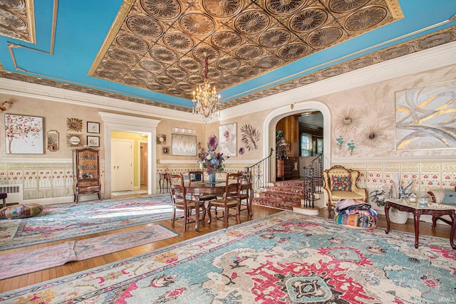 dining area featuring crown molding, a towering ceiling, a notable chandelier, and hardwood / wood-style flooring