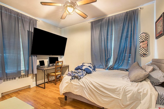 bedroom featuring radiator heating unit, hardwood / wood-style flooring, and ceiling fan