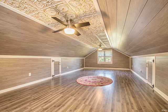 additional living space with wooden walls, wooden ceiling, lofted ceiling, dark hardwood / wood-style floors, and ceiling fan