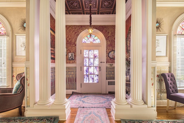 foyer with plenty of natural light, ornamental molding, hardwood / wood-style flooring, and ornate columns