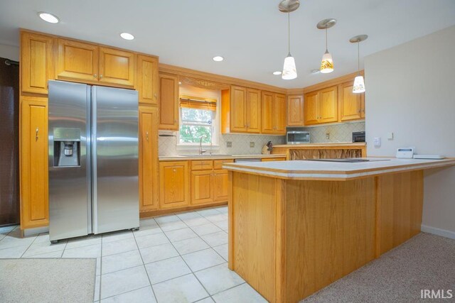 kitchen with stainless steel refrigerator with ice dispenser, pendant lighting, tasteful backsplash, sink, and light tile patterned flooring