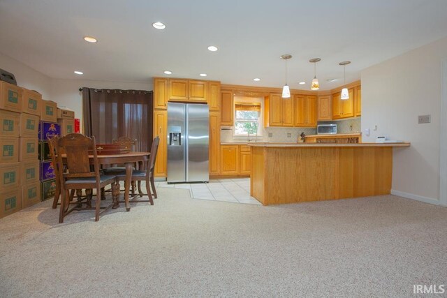 kitchen featuring hanging light fixtures, light colored carpet, stainless steel appliances, sink, and kitchen peninsula