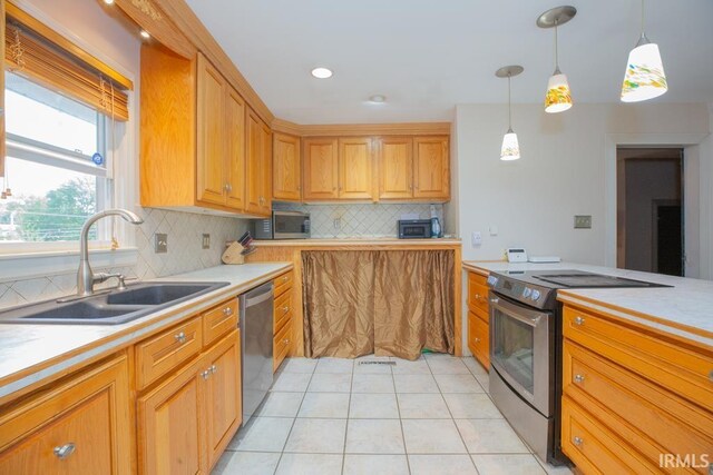 kitchen with tasteful backsplash, light tile patterned floors, stainless steel appliances, sink, and hanging light fixtures