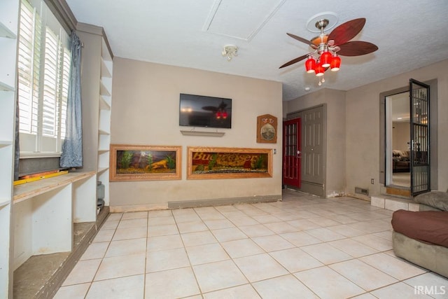 living room with ceiling fan, light tile patterned floors, and a textured ceiling