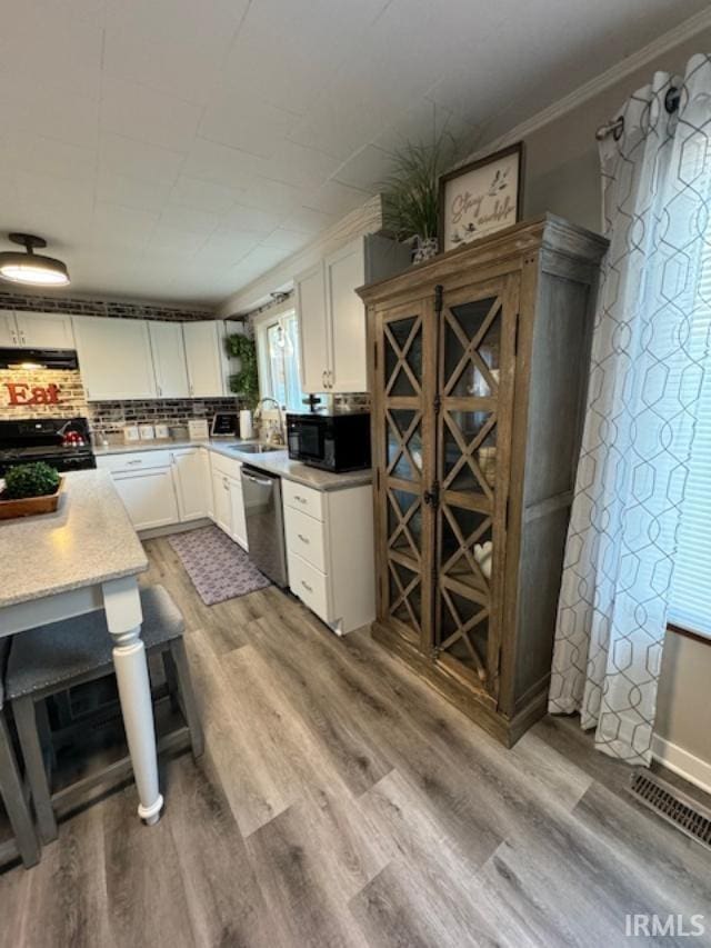 kitchen featuring light wood-type flooring, crown molding, black appliances, sink, and white cabinets