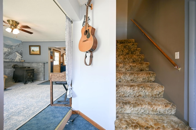 stairs featuring a wood stove, ceiling fan, and carpet floors