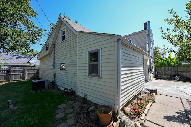 view of side of property with a lawn, a patio area, and central air condition unit