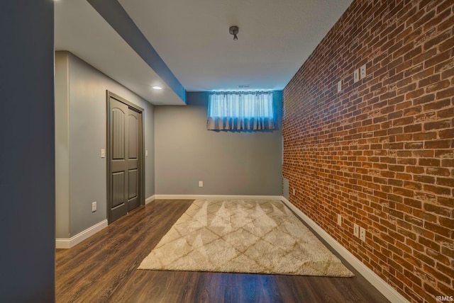 hallway with dark hardwood / wood-style floors and brick wall