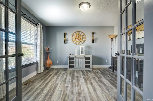 interior space with french doors, a textured ceiling, and hardwood / wood-style flooring