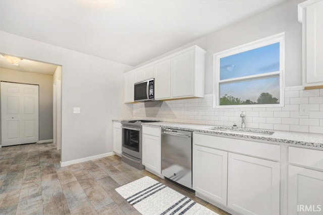 kitchen with tasteful backsplash, white cabinetry, appliances with stainless steel finishes, and sink