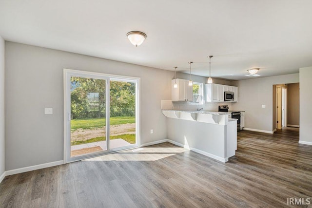 kitchen featuring electric stove, white cabinetry, hanging light fixtures, a kitchen bar, and kitchen peninsula