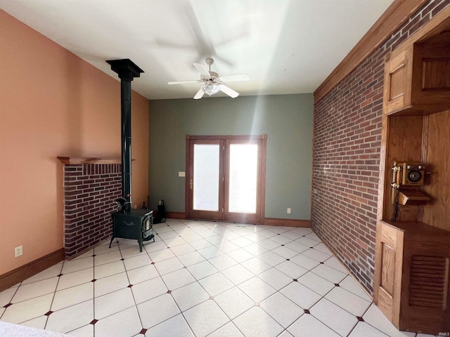 living room featuring brick wall, ceiling fan, and a wood stove