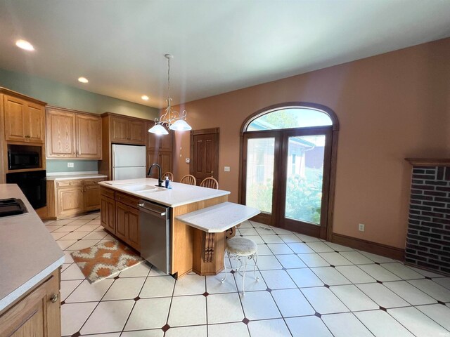 kitchen with decorative light fixtures, black appliances, a kitchen island with sink, sink, and a chandelier