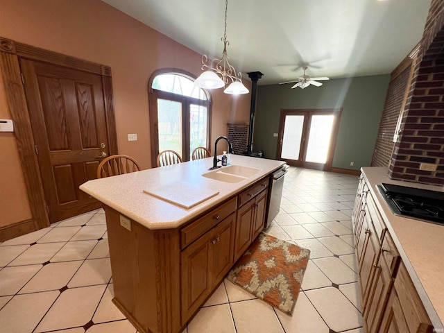 kitchen featuring ceiling fan with notable chandelier, sink, gas cooktop, a kitchen island with sink, and stainless steel dishwasher