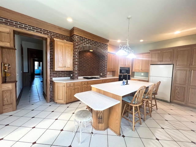 kitchen featuring a center island with sink, black appliances, brick wall, and decorative light fixtures