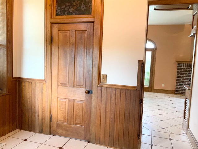 hall with light tile patterned floors and wooden walls