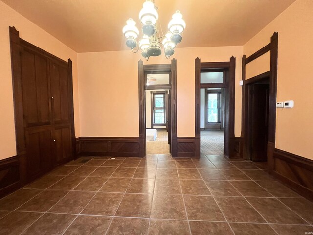 tiled spare room with an inviting chandelier