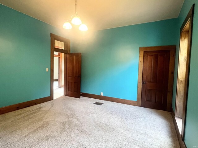 unfurnished room with carpet flooring and an inviting chandelier