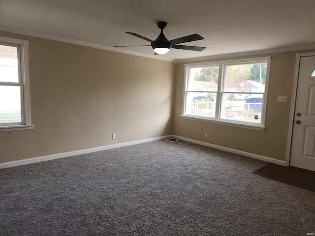 empty room with ceiling fan, dark carpet, and ornamental molding