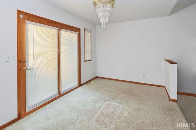 carpeted spare room featuring a chandelier