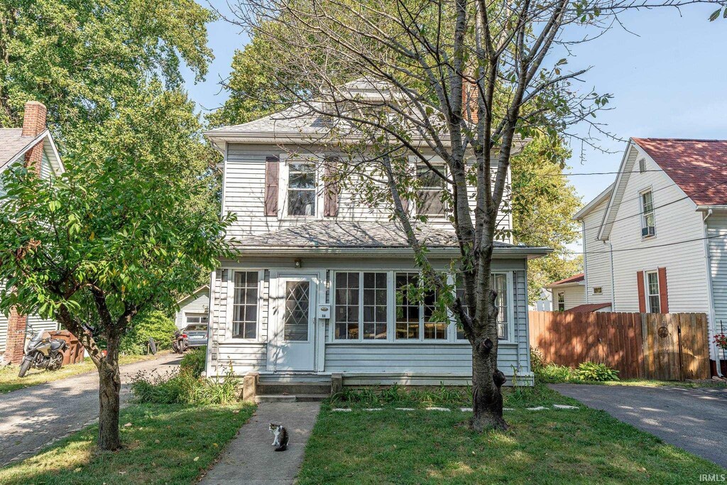 american foursquare style home with a front yard, driveway, fence, and entry steps