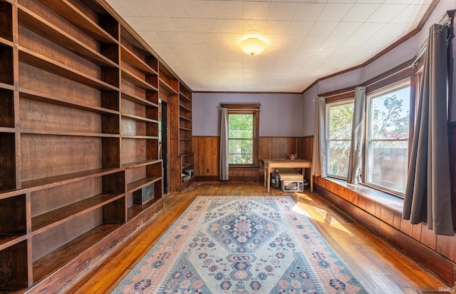 living area featuring built in features, hardwood / wood-style flooring, wooden walls, and ornamental molding