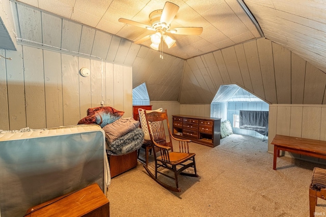 carpeted bedroom featuring vaulted ceiling, wood walls, and ceiling fan