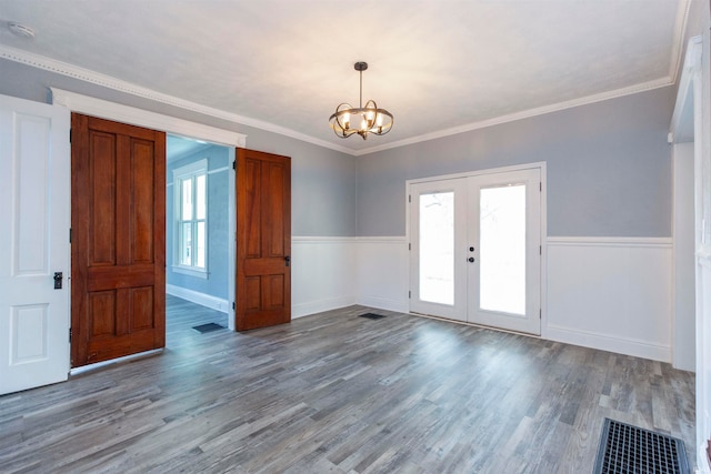 unfurnished room with a notable chandelier, light hardwood / wood-style floors, ornamental molding, and french doors