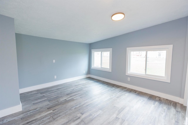 unfurnished room featuring vaulted ceiling and hardwood / wood-style flooring