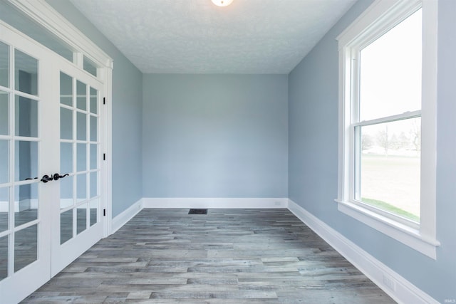 spare room with french doors, light hardwood / wood-style floors, and a textured ceiling