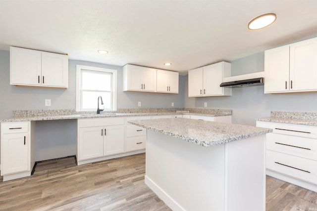 kitchen featuring a kitchen island, light wood-type flooring, white cabinetry, and sink