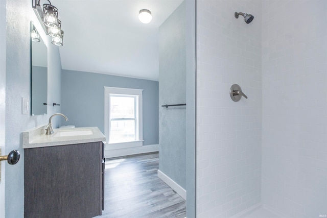 bathroom with tiled shower, hardwood / wood-style floors, and vanity