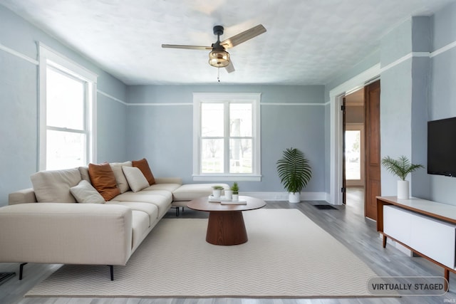 living room featuring ceiling fan, light hardwood / wood-style floors, and a wealth of natural light