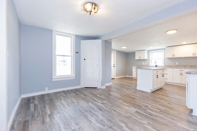 kitchen with white cabinets, a center island, light hardwood / wood-style floors, and plenty of natural light