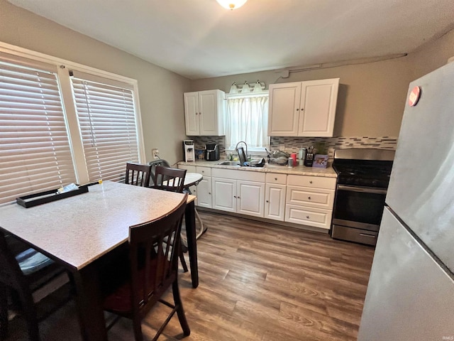 kitchen with hardwood / wood-style floors, stainless steel range, sink, white refrigerator, and white cabinets