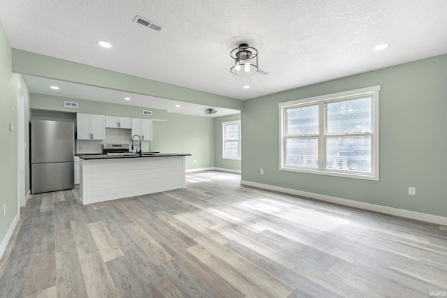 3615 Lindbergh Blvd, Fort Wayne, IN 46806 - unfurnished living room featuring a sink, light wood-style floors, baseboards, recessed lighting, and a textured ceiling