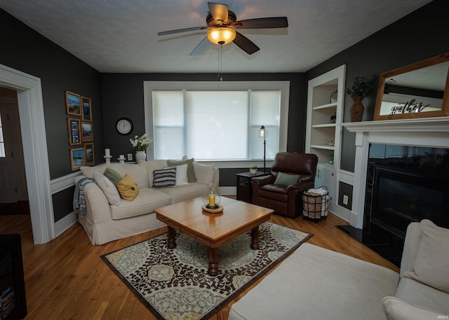 living room featuring wood-type flooring, a tile fireplace, and ceiling fan