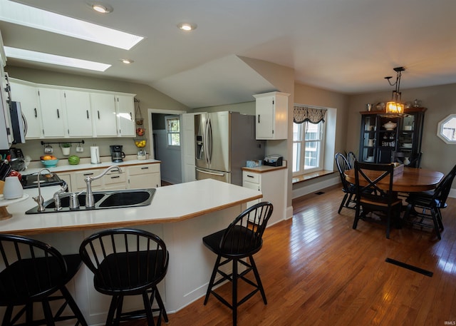 kitchen with a healthy amount of sunlight, appliances with stainless steel finishes, dark hardwood / wood-style flooring, and lofted ceiling with skylight