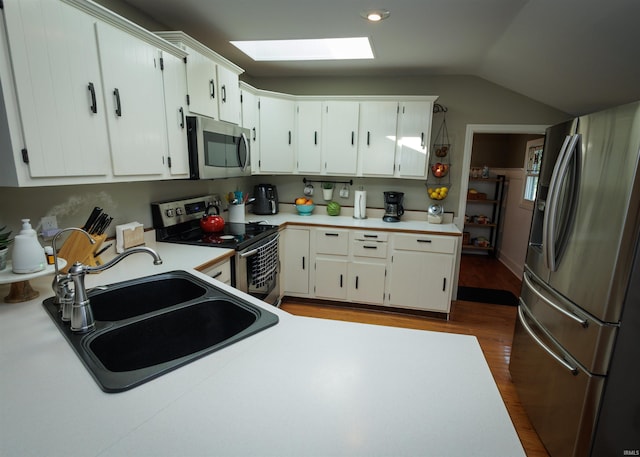 kitchen featuring stainless steel appliances, sink, white cabinets, and lofted ceiling with skylight