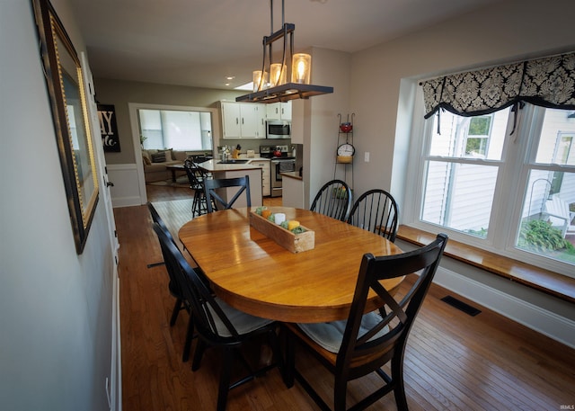 dining area with wood-type flooring and an inviting chandelier