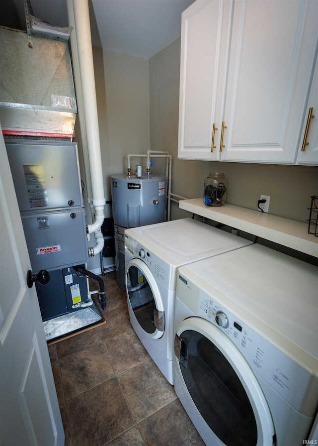 clothes washing area featuring washer and dryer, cabinets, and electric water heater