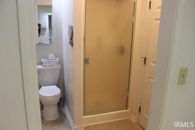 bathroom featuring toilet, an enclosed shower, and tile patterned floors