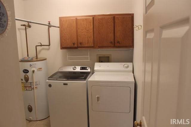 clothes washing area with washer and clothes dryer, cabinets, and water heater