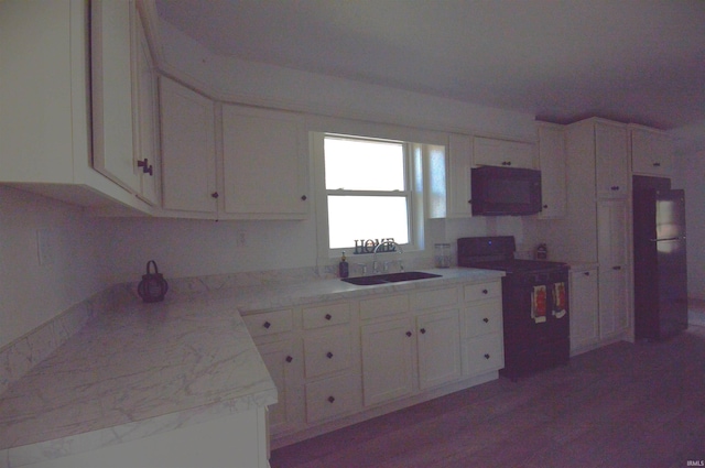 kitchen featuring sink, stove, refrigerator, and white cabinetry