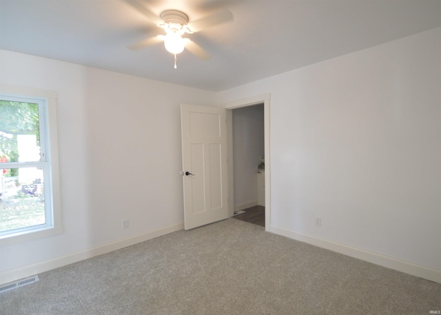 empty room featuring ceiling fan and light colored carpet